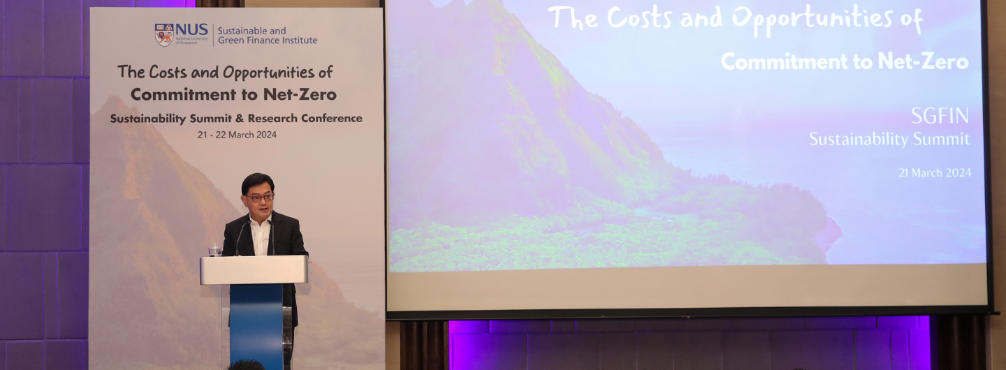 Speaker at podium presents at NUS Sustainable Green Finance Summit. Projected screen displays event info.